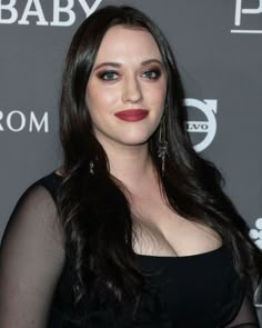 a woman with long dark hair wearing a black dress and red lipstick is posing for the camera