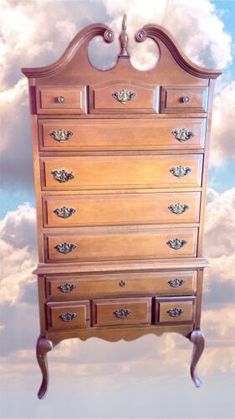 a wooden dresser with many drawers on it's side and clouds in the background