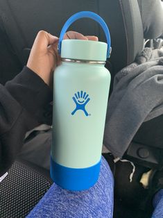 a person holding onto a blue and white water bottle in their hand with the lid up