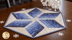 a blue and white quilted table topper sitting on top of a wooden table