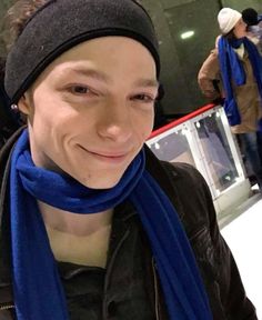 a man with a blue scarf around his neck and wearing a beanie on top of his head