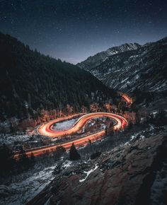 an aerial view of a winding road in the mountains at night with stars above it