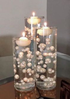 two glass vases filled with pearls on top of a table