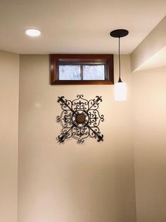 a clock mounted to the side of a wall next to a window and light fixture