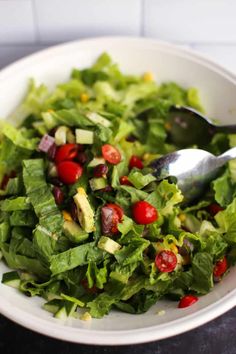 a salad with lettuce and tomatoes in a white bowl