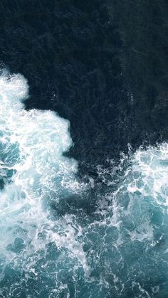 an aerial view of the ocean with waves coming in and crashing on it's surface