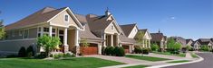 a row of houses with trees and bushes in front