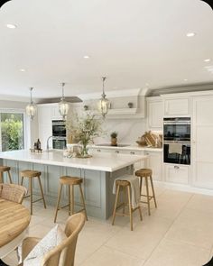 a large kitchen with an island and bar stools in it's center area