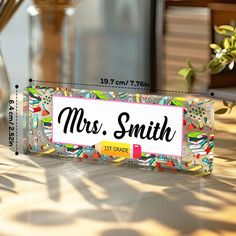 a sign that says mrs smith on it sitting on a table next to a potted plant