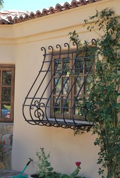 an iron window sill on the side of a building next to a potted plant