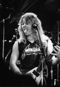 a black and white photo of a person playing guitar in front of a microphone on stage