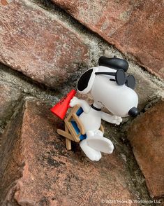 a toy dog sitting on top of a wooden chair in front of a rock wall