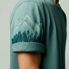 the back of a man's green shirt with trees and mountains printed on it