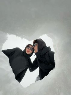 two people are standing in the snow with their faces close together