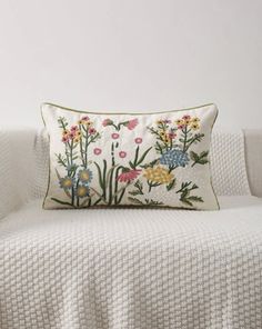 a white couch with a flowered pillow on it's back and the cover pulled down