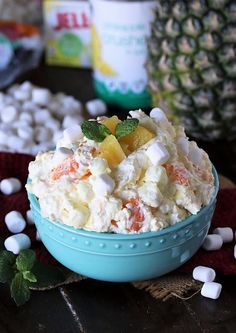 a blue bowl filled with fruit and marshmallows