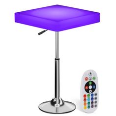 a remote control sitting on top of a table next to a purple square shaped light