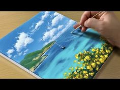 a person is holding a paintbrush and drawing on a piece of paper with yellow flowers