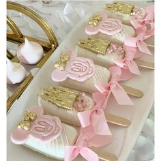 pink and gold cake pops with monogrammed initials on them are arranged in a row