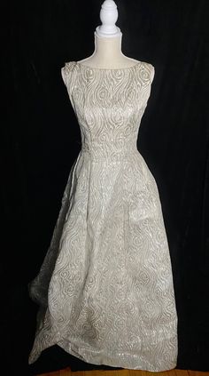 "Fabulous 1960's metallic silver and white Emma Domb formal dress with low back and high neckline. Zipper up the back and tulle under the skirt to help keep it full. Skirt near the hem has an orange spot about the size of a quarter Women's small/medium 36\" bust 27\" waist Open hips 60\" shoulder to hem" Vintage Silver Dress, Fitted Gown With Full Skirt For Party, White A-line Fitted Mother Of The Bride Dress, White A-line Vintage Dress For Party, Fitted Full Skirt Evening Wedding Dress, Silver Ball Gown For Evening, Elegant Vintage Ball Gown For Party, Formal Silver Ball Gown Evening Dress, Silver Ball Gown Evening Dress For Formal Occasions