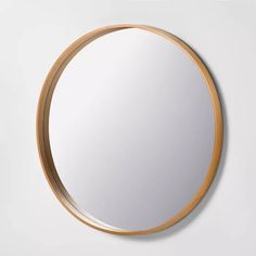 a round mirror on the wall with wooden trim around it and a light wood frame