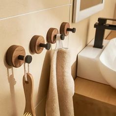 three wooden spoons are hanging on the wall next to towels and toothbrushes