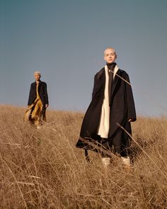 two people standing in tall grass on a sunny day