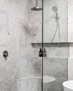 a bathroom with marble walls and flooring next to a bathtub in the shower