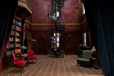 a spiral staircase in the middle of a room with chairs and bookshelves on either side