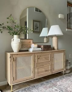 a large mirror sitting on top of a wooden dresser next to a vase and lamp