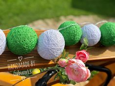 several balls of yarn sitting on top of a wooden bench next to flowers and scissors