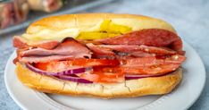 a sandwich with meat, tomatoes and onions on a plate