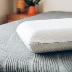 a close up of a pillow on a bed with a plant in the back ground