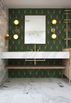 a bathroom with marble counter tops and green wallpaper, along with two gold - toned lights