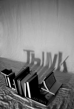 three books are sitting on a table with their shadows