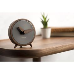 an alarm clock sitting on top of a wooden table next to a potted plant