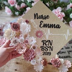 a graduation cap with flowers on it is being held up by someone's hand