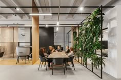 people sitting at a table in an office with plants growing on the wall behind them