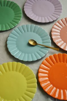 colorful plates with a gold spoon on top of them next to another plate that has four different colors