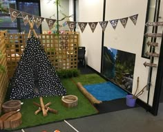 an indoor play area with fake grass and wooden logs