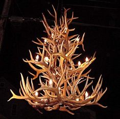 a chandelier made out of antlers with candles lit up in the dark