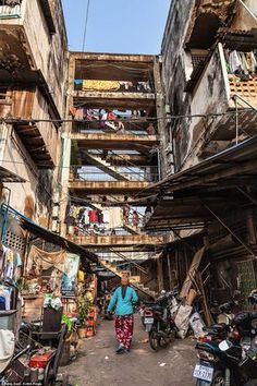 a woman walking down an alley way with lots of balconies on the roof