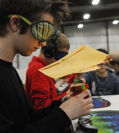 a young man wearing sunglasses and holding a piece of paper in front of his face