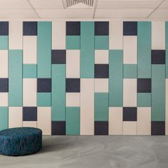 a blue ottoman sitting in front of a wall with geometric tiles on it's sides