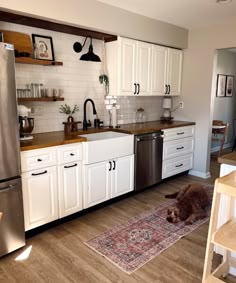 a dog laying on the kitchen floor in front of an oven and dishwasher