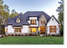 a large white house with lots of windows on it's front lawn and trees in the background