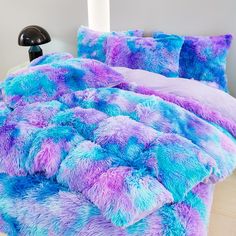 a purple and blue comforter set on a bed