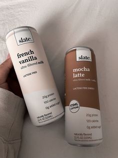 two cans of chocolate latte sitting next to each other on top of a bed