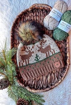 two balls of yarn sitting on top of a basket next to pine cones and needles