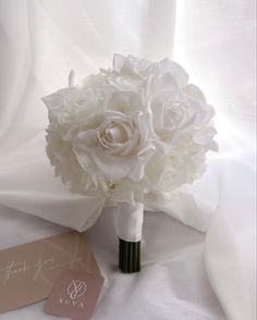 a bouquet of white flowers sitting on top of a bed next to a card and envelope